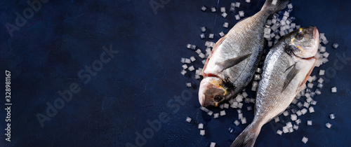 Two raw dorado fishes on wooden dark blue background