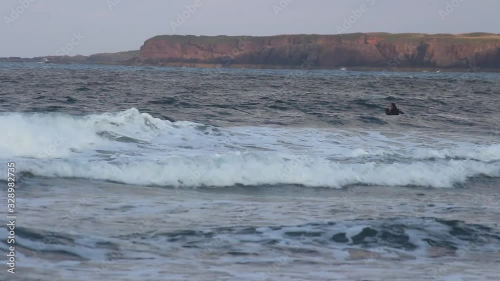 Stormy seas in englands north east coast. Two surfers prepare to hit the waves. High waves. Northumberland. St Abbs Head. SIte of New Asguard in The Avengers Thor MCU. Stormy seas in englands north east coast. Two surfers prepare to hit the waves. High waves. Northumberland. St Abbs Head. SIte of New Asguard in The Avengers Thor MCU.