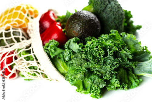 Eco friendly mesh bag with organic vegetables: Kale salad, broccoli, avocado, bell peppers on a white background. Zero waste concept. Healthy clean eating diet and detox. Top view, Copy space