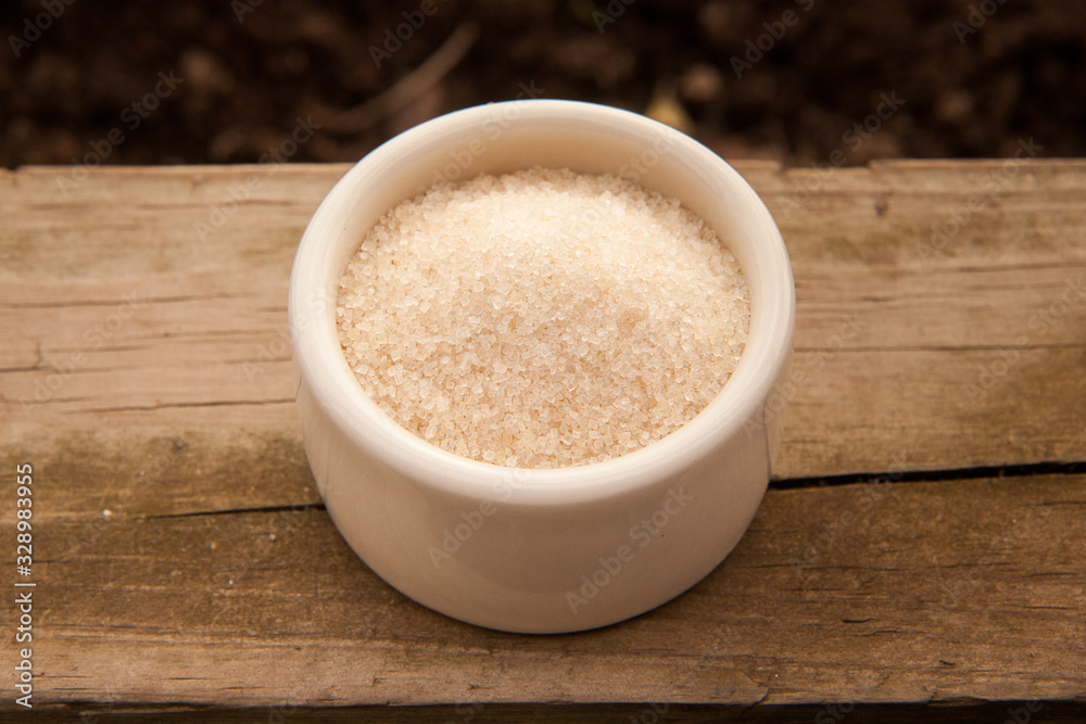 Raw Cane Sugar in a Bowl on a Wooden Plank Raw Cane Sugar in a Bowl on a Wooden Plank