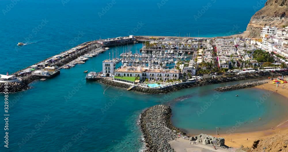 View of urban seaside port and harbor in Mogan Playa city with boats and part of coast captured from the air in Gran Canary island 4k slow motion capture at 60fps. View of urban seaside port and harbor in Mogan Playa city with boats and part of coast captured from the air in Gran Canary island 4k slow motion capture at 60fps.