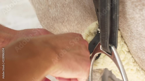 man preparing saddle for riding horse