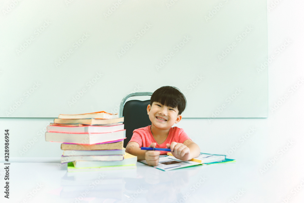 Happy kid sitting and read a book beside a large pile of books. Children and learning concept. Happy kid sitting and read a book beside a large pile of books. Children and learning concept.