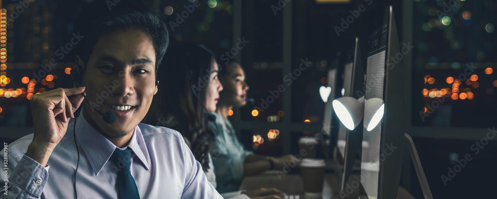 Banner of Asian Male customer care service with businesswoman smiling and working hard late in night shift at office,call center department,worker and overtime,team work with colleagues for success