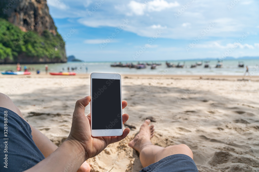 Young man traveler using  smartphone at tropical sand beach, Summer vacation concept