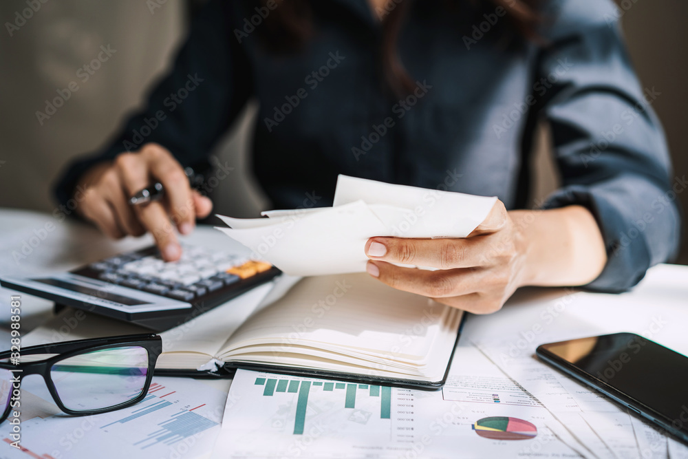Stressed young woman checking bills, taxes, bank account balance and calculating expenses in the living room at home Stressed young woman checking bills, taxes, bank account balance and calculating expenses in the living room at home
