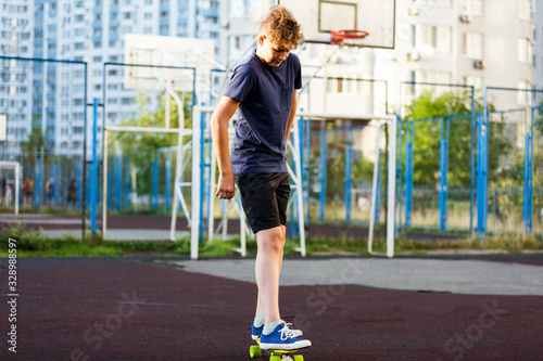 Cute cheerful smiling Boy in blue t shirt sneakers riding on yellow skateboard. Active urban lifestyle of youth, training, hobby, activity concept. Active outdoor sport for kids. Child skateboarding. 
