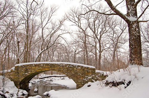 Photo Scenic winter landscape with stone bridge over a flowing creek.