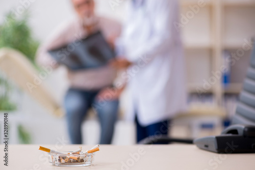 Принти на полотні Young male doctor and old patient in antismoking concept