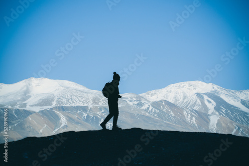 Silhouette of woman hiker stands on the rock in the beautiful mountains view of snowy Tso Moriri Lake in Leh Ladakh india, success concept © DN6