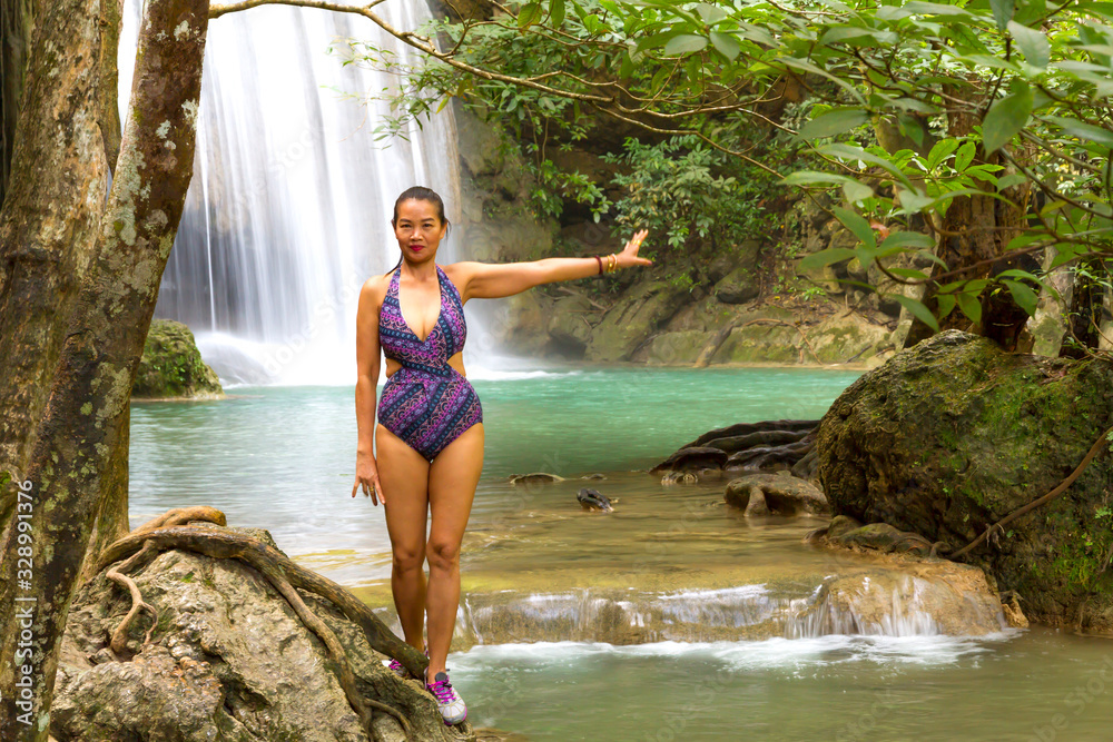 Fototapeta premium Woman with swimsuit stand smile at Erawan Waterfall and natural