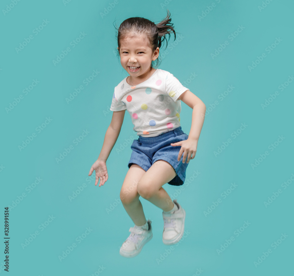 Excited Asian little girl jumping in mid-air, empty space in studio shot isolated on colorful blue background Excited Asian little girl jumping in mid-air, empty space in studio shot isolated on colorful blue background