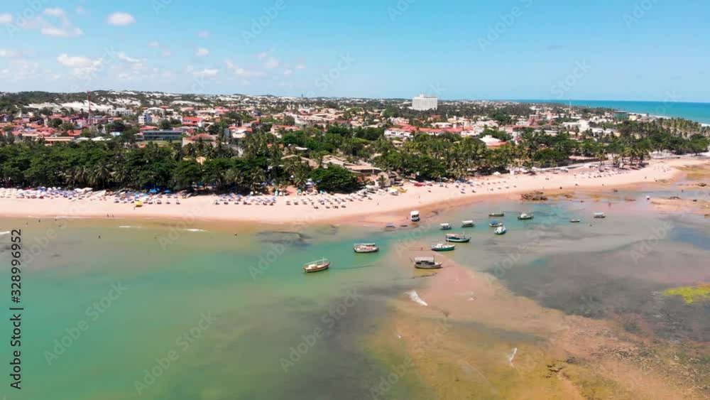 Orbital drone flight showing the Itapuã seashore. Fishing boats sunny day and umbrellas in the sand. Orbital drone flight showing the Itapuã seashore. Fishing boats sunny day and umbrellas in the sand.