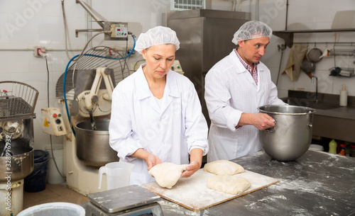 Man and woman prepare bread in the kitchen of the bakery