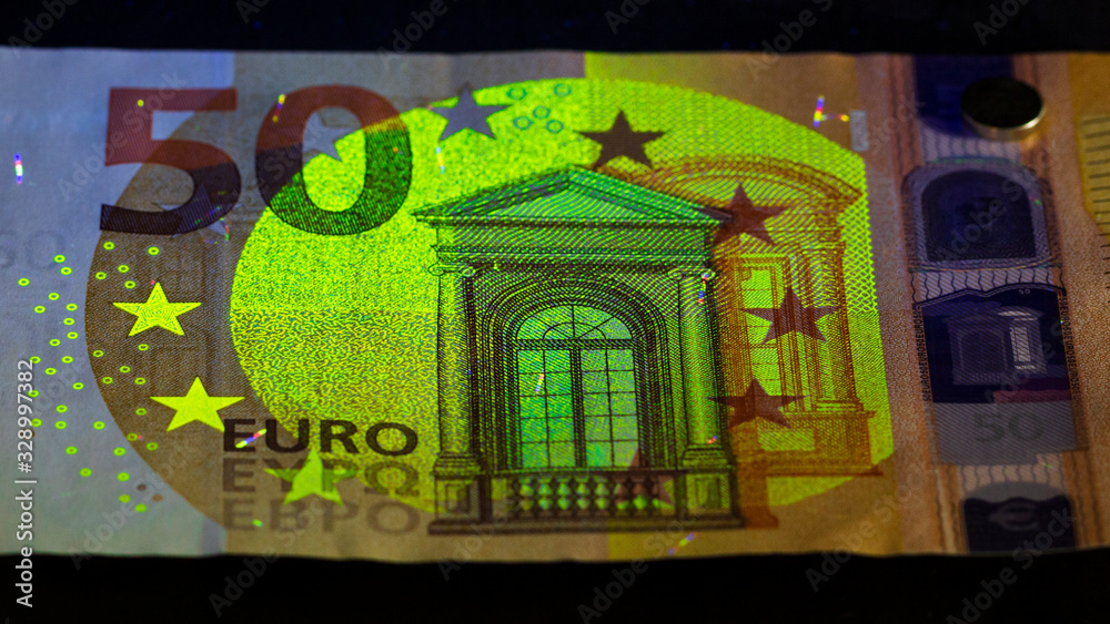 checking money held in a human hand . Euro currency in UV light protection