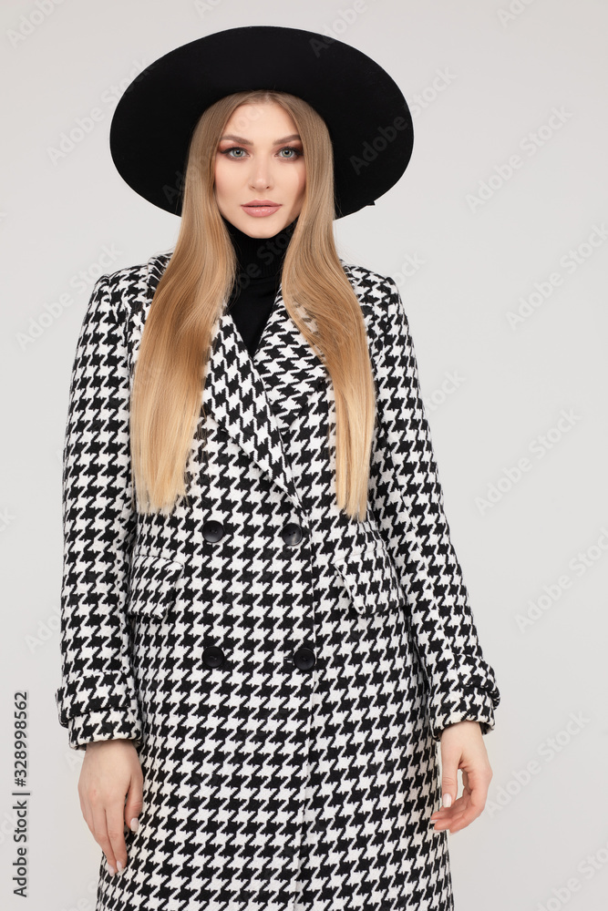 Trendy beautiful female model in hat at stylish posing isolated at white studio background medium long shot. Adorable young blonde woman standing in classy autumn clothes Trendy beautiful female model in hat at stylish posing isolated at white studio background medium long shot. Adorable young blonde woman standing in classy autumn clothes