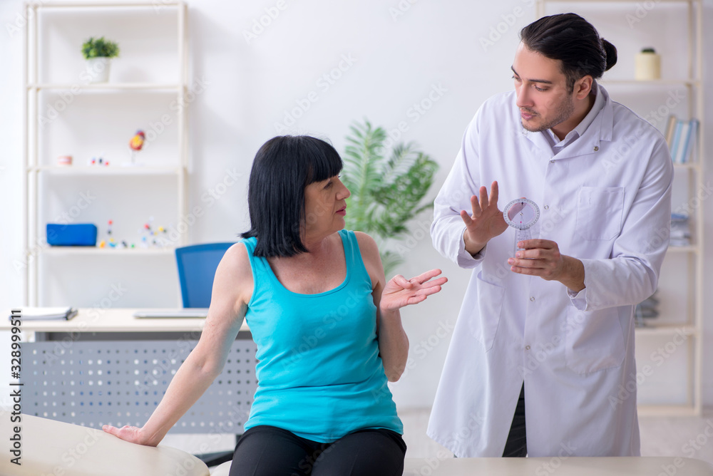 Fototapeta premium Young male doctor examining old female patient