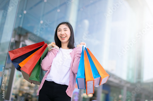 Portrait of a happy Asian pretty girl holding shopping bags background shopping mall concept.