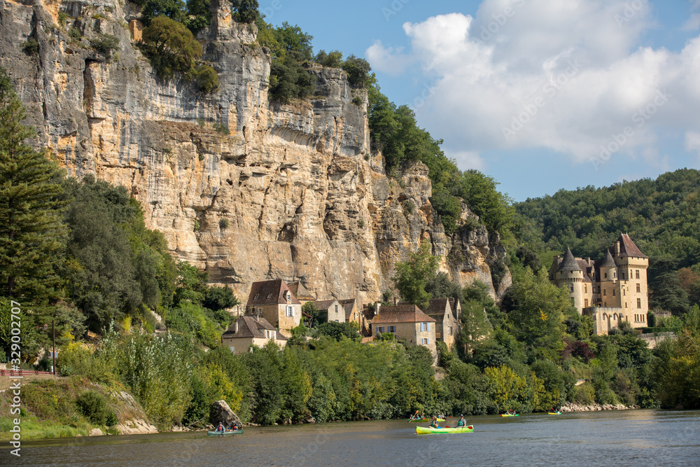  Canoeing on the river Dordogne at La Roque-Gageac and Chateau La Malartrie in the background. Aquitaine, France