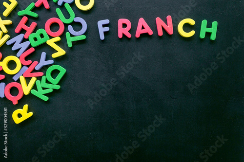 Learn French. Concept with letters on black background top-down copy space