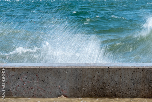 Waves hit the concrete wall and splashing sea water.