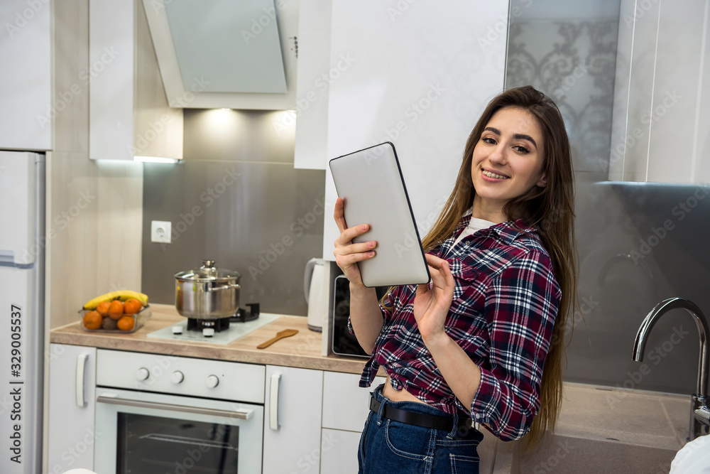 Young woman using a tablet computer to cook different vegetables in her kitchen for everything about healthy nutrition. Young woman using a tablet computer to cook different vegetables in her kitchen for everything about healthy nutrition.