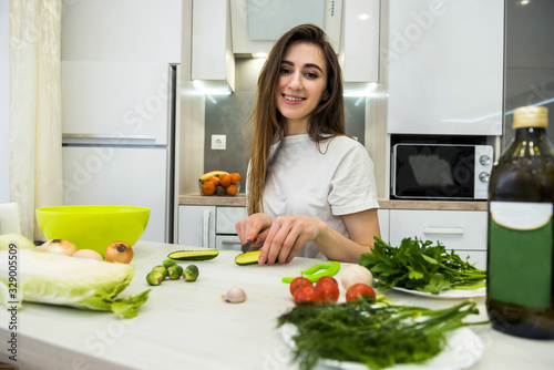 cute girl prepares a salad of different vegetables and greens for a healthy lifestyle.
