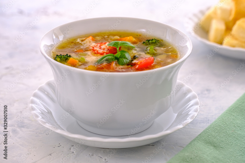 Hot and fragrant Italian ministrone soup with cherry tomatoes, basil and parmesan in a white cup Hot and fragrant Italian ministrone soup with cherry tomatoes, basil and parmesan in a white cup