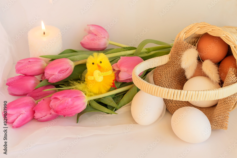 Arrangement of pink tulips and fresh eggs in a wicker basket for Easter.