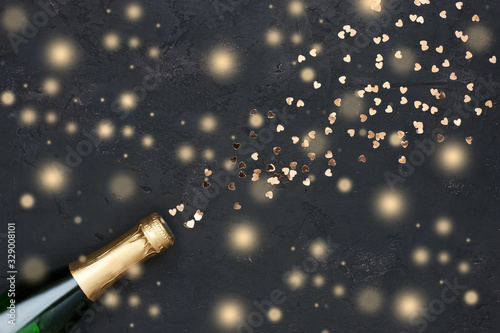  Champagne bottle with golden confetti on color background. Flat lay photo
