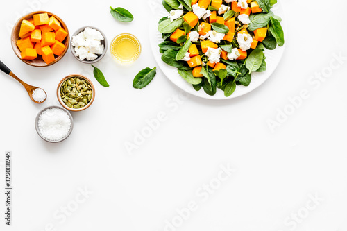 Salad with pumpkin and basil - near ingredients - on white background top-down copy space © 9dreamstudio