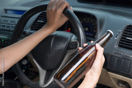 Female Driving Car Holding Alcoholic Bottle.