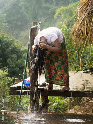 Jeune fille Lahu se lavant les cheveux dans un village de la région de Chiang Raï, Thaïlande. photo