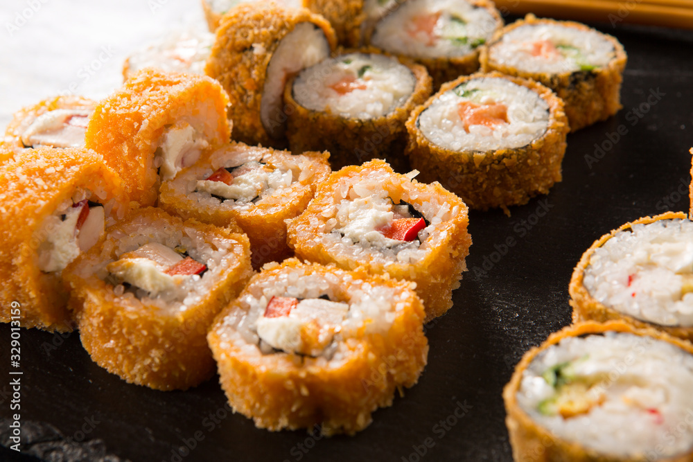 Set of baked sushi rolls with wasabi and ginger on a black background. Japanese oriental cuisine Set of baked sushi rolls with wasabi and ginger on a black background. Japanese oriental cuisine