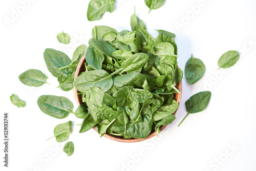 Fresh spinach in a wooden bowl isolated on white background