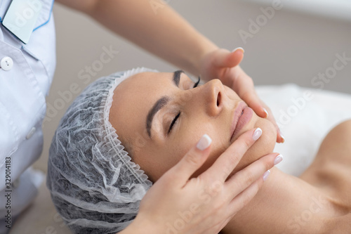 Woman closing her eyes while enjoying face massage