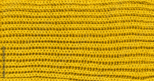 Vibrant yellow texture knitted wool scarf. Yellow textile background knitwear. Close-up