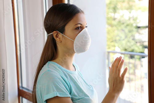 COVID-19 Woman home isolation auto quarantine wearing face mask protective for spreading of disease virus SARS-CoV-2. Girl voluntary isolation surgical mask on face against Coronavirus Disease 2019.