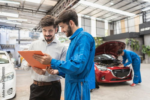 A mechanic and customer look at paper. service car in garage is paper checklist car. service car, repair, maintenance concept.Technician doing the checklist for repair machine a car in the garage.