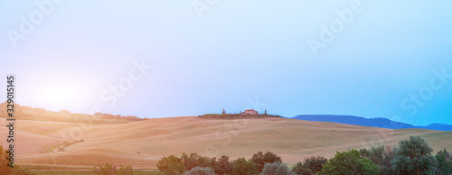Tuscany  rural landscape. Rolling hills  countryside farm  cypresses trees  green field on warm sunset. Italy  Europe.