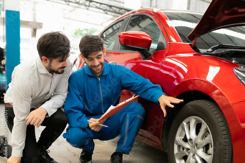 A mechanic male handsome smiling maintenance service repair car to customer in garage. Automotive technician are checking tires with customers. concept checklist car vehicle repair maintenance..