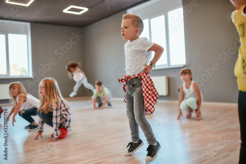 Fototapeta Naklejka Na Ścianę i Meble -  Group of cute little boys and girls studying modern dance in studio. Choreography class