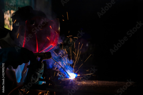 A craftman is welding with workpiece steel.Working person About welder steel Using electric welding machine There are lines of light coming out and safety equipment in factory industry..