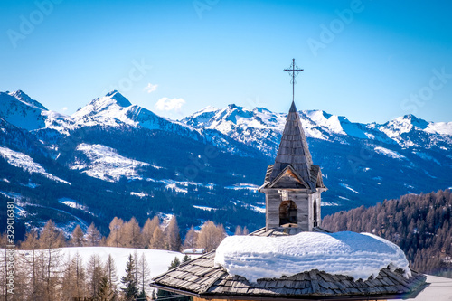 Sunny winter landscape with wooden roof and cross at Ski Area in Dolomites, Italy - Alpe Lusia. Ski resort in val di Fassa near Moena