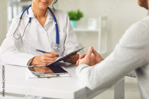Female doctor therapist gross allergist nutritionist otolaryngologist and male patient sitting at a table in a clinic office
