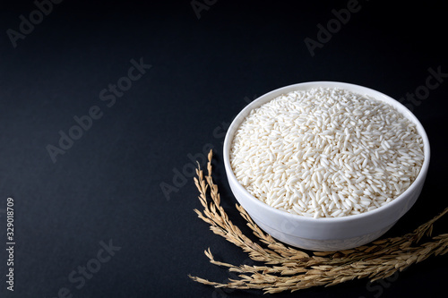 Thai glutinous rice or sticky rice in white ceramic bowl on black background. 45 degree angle. close up shot.