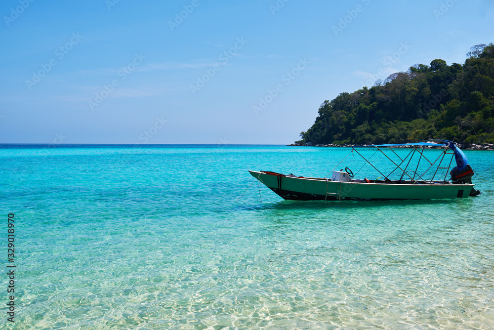 Beautiful nature landscape. White sandy beach and a boat in the turquoise sea. Paradise island. Perfect getaway. Travel concept and idea.