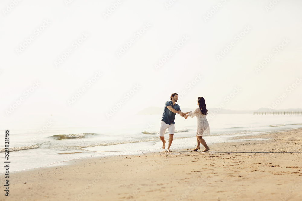Happy couple walking along the sea, holding hands. Love story