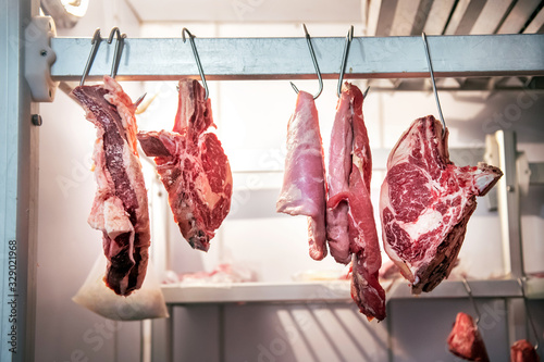 фотографія Pieces of fresh beef hanging in refrigerator
