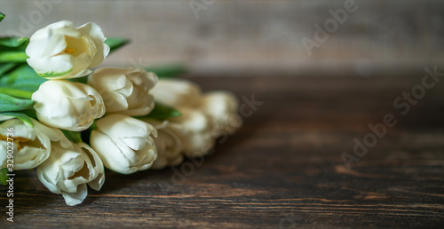 Spring flowers. Bouquet of white tulips on brown wooden table. Mother's Day and Valentines Day background. Rustic style. Copy space for your text.